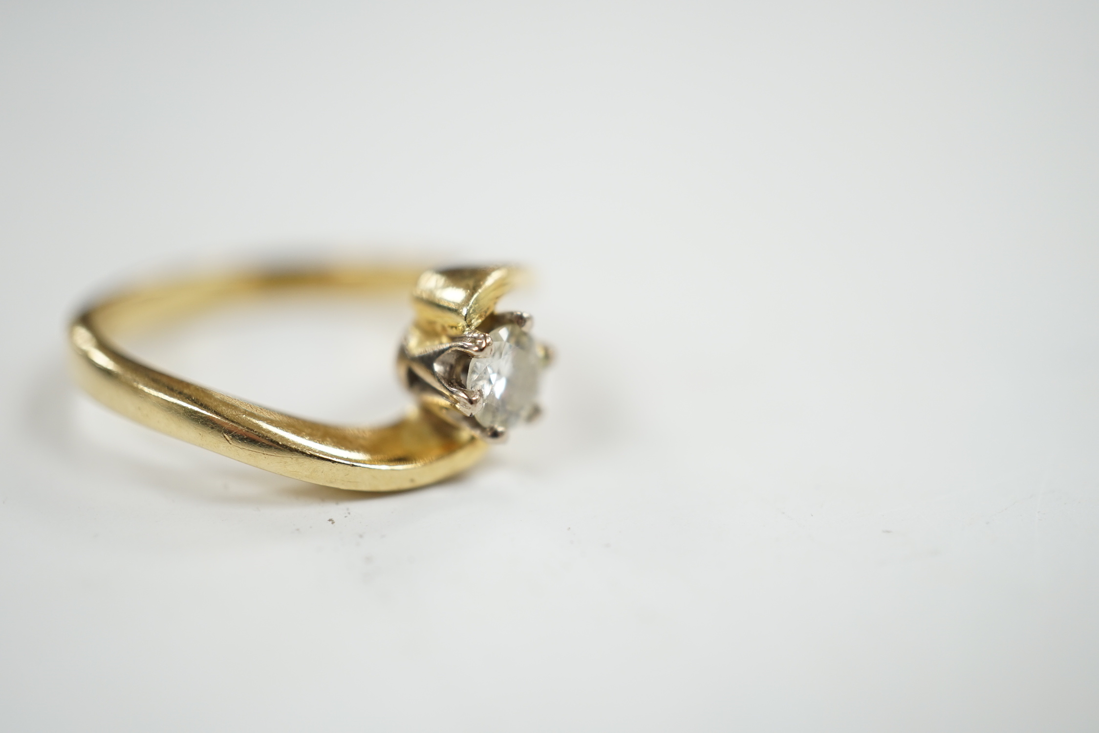 A modern 18ct gold and solitaire diamond set ring, with crossover shoulders, size K, gross weight 4 grams.